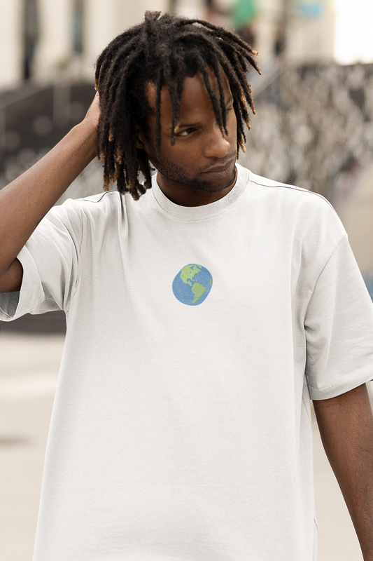Back view of a man wearing a Pixalflux white oversized t-shirt featuring a colorful four-panel graphic with a sun, ocean wave, and palm tree.