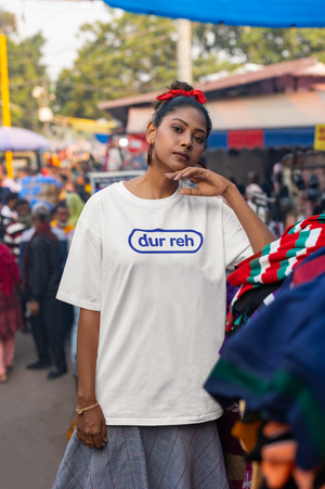 Woman wearing a white t-shirt with 'dur reh' logo in a crowded outdoor setting